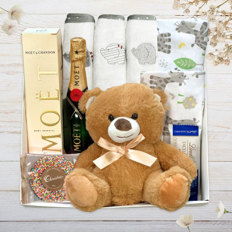 Collection of gifts including a teddy bear, Lindt chocolate, moet with teddy bear from The Baby Gift Company.