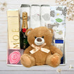 Collection of gifts including a teddy bear, Lindt Lindor chocolate box, moet with teddy bear from The Baby Gift Company.