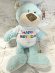 Light blue teddy bear with a 'Happy Birthday' shirt on a marble surface