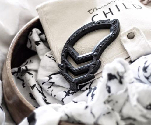 Black teether toy item on a textured surface with 'CHILD' text in the background