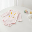 Baby pink and white striped onesie with bunny face on a table