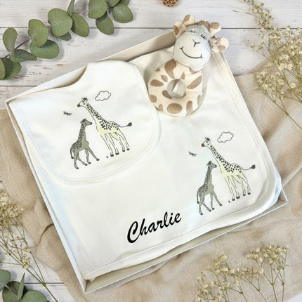 A collection of baby essentials with giraffe prints and rattle in a gift box