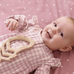 Baby girl with Feather Teether toy on pink blanket