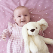 Baby girl holding white bunny on pink dotty blanket