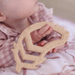 Baby girl holding Feather Teether toy