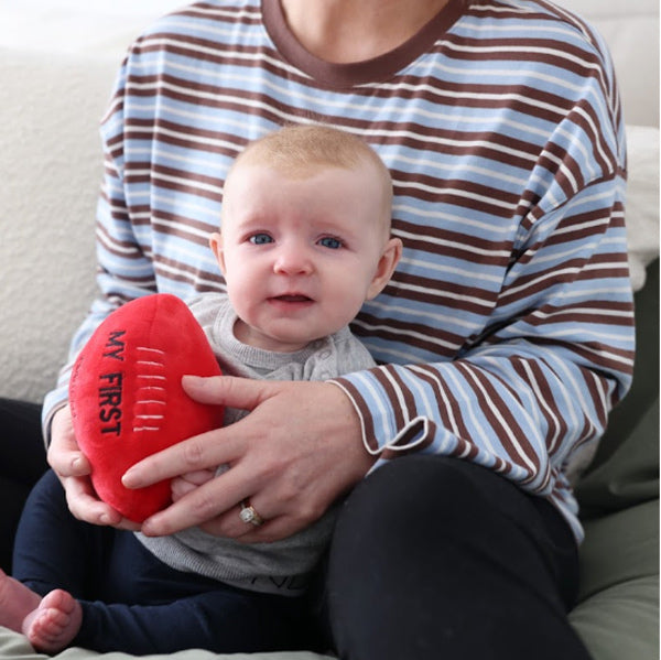 Mum and baby holding Baby's red Footy