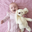 Baby girl holding white bunny on pink blanket