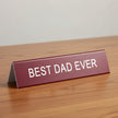 Red sign with 'BEST DAD EVER' text on a table background