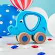 Blue elephant toy with wooden wheels on a light blue background
