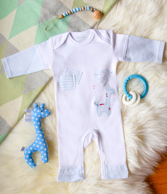 White baby romper with cartoon designs on a textured surface with toys around