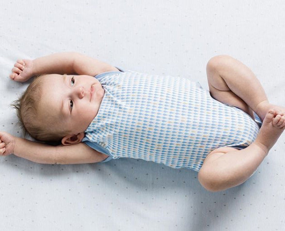 baby laying down in blue romper