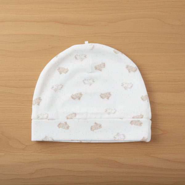 White baby hat with small bear pattern on a table