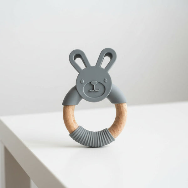 Gray silicone teething ring with wooden handle shaped like a bunny on a white background