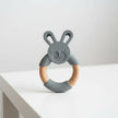 Gray silicone teething ring with wooden handle shaped like a bunny on a white background