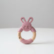 Pink bunny-shaped teething ring with wooden ring on a table background