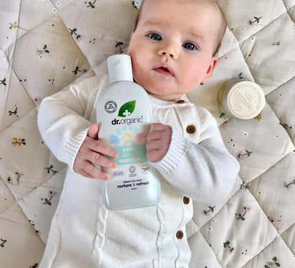 Baby holding a Dr. Organic product on a patterned blanket