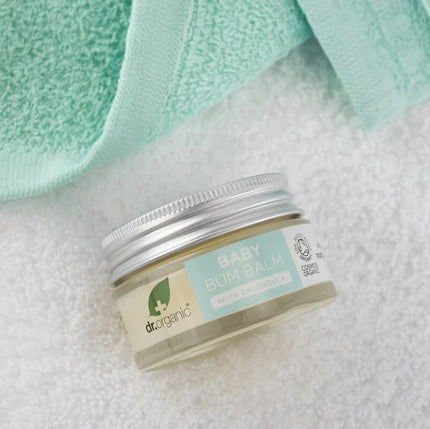 Jar of baby bum balm with a green towel in the background