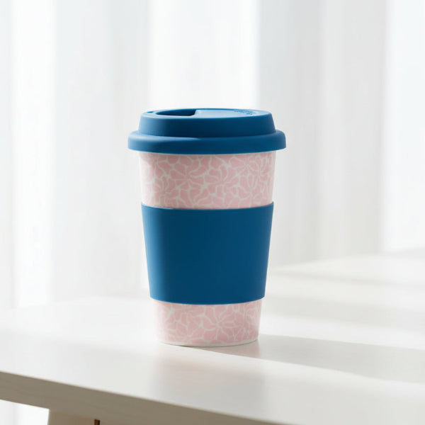 Reusable coffee cup with pink pattern and blue accents on a white background