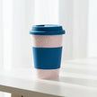 Reusable coffee cup with pink pattern and blue accents on a white background
