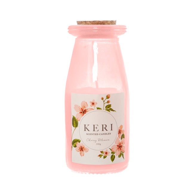 Pink candle in a bottle with a floral label on a white background