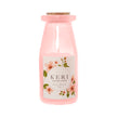 Pink candle in a bottle with a floral label on a white background