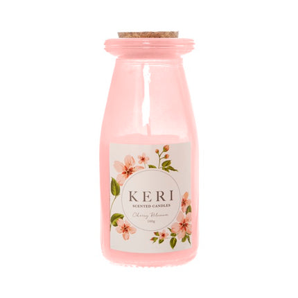Pink candle in a bottle with a floral label on a white background