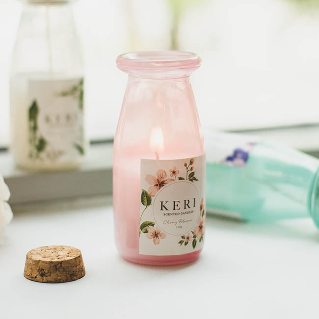 Pink bottle candle with floral label on a white surface