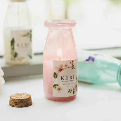 Pink bottle candle with floral label on a white surface