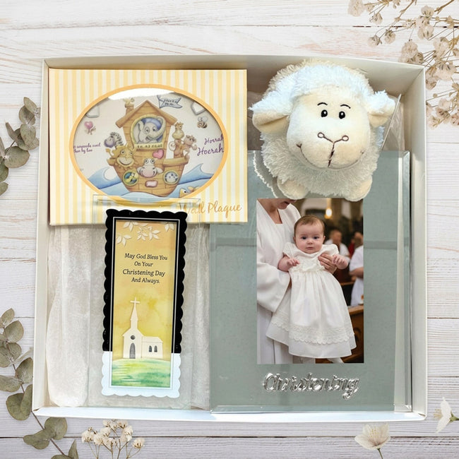 Gift set with christening photo frame, card, and plush lamb toy in a baby gift box on a wooden surface.