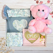 baby gift set with teddy bear and baby clothes in gift box on wooden table