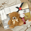Luxury gift box with moet champagne, teddy bear and baby items on wooden surface