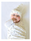 Newborn baby wrapped in a patterned blanket and wearing a matching hat on a light background