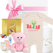 Baby gift set with onesie, teddy bear, and other gifts for girl in gift box on a white background