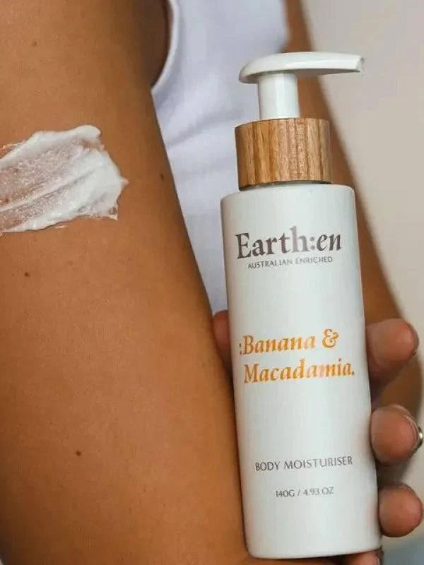 Earth:en Banana & Macadamia body moisturizer bottle held against skin with a visible application of product.