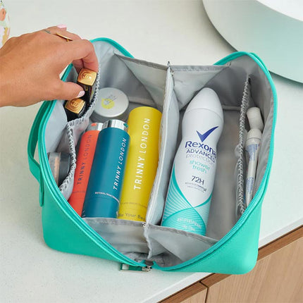 Open teal toiletry bag with various skincare products including Trinny London and Rexona.
