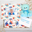 Baby gift set with teddy bear, photo frame, and blanket featuring animal patterns on a wooden surface.