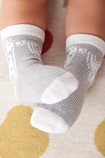 Baby's feet wearing gray and white socks on a patterned rug