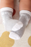 Baby's feet wearing gray and white socks on a patterned rug