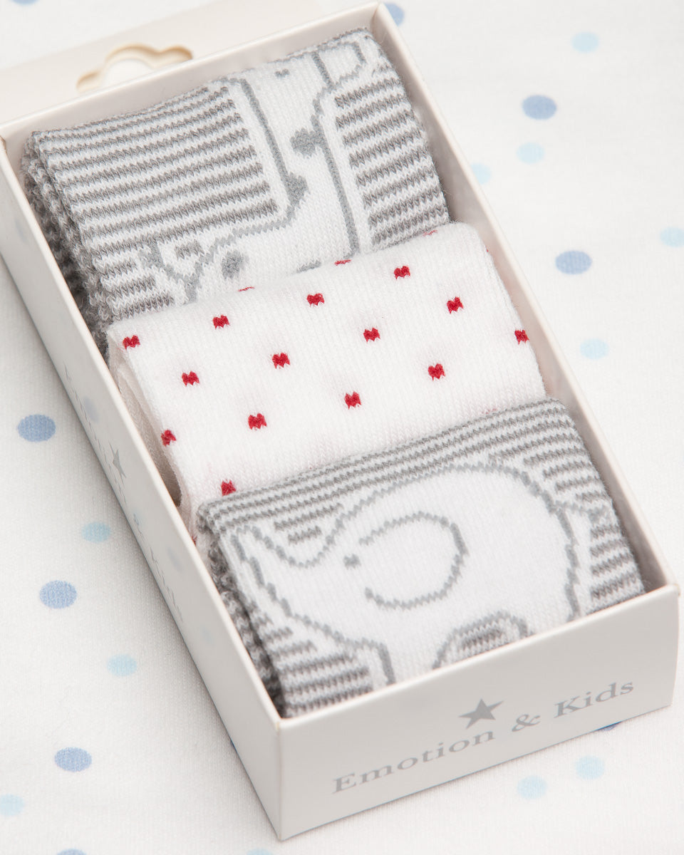 Set of baby socks with gray and white patterns in a box on a polka dot background