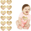 Baby in a pink onesie with 'seven months' printed on it, surrounded by heart-shaped milestone stickers.
