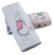 Two folded towels with a flopsy rabbit design and nature-themed pattern on a white background