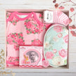 Baby gift set with floral-themed items in a box on a wooden surface.
