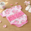 Floral baby outfit with ruffles on a wooden table