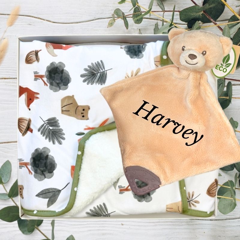 Green forest baby blanket and teddy bear with 'Harvey' embroidered, in a box with greenery background
