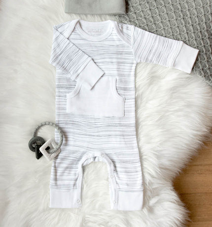 White baby onesie with black stripes on a textured surface