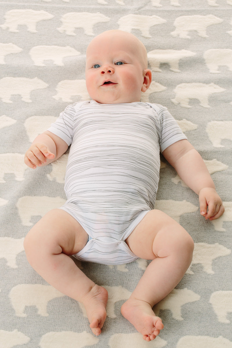 Baby lying on a patterned rug with bear designs