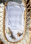 Baby outfit with striped onesie and toys in a wicker crib