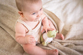 Baby holding a plush toy on a soft blanket