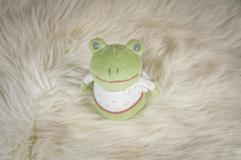 Green frog plush toy on a fluffy white surface