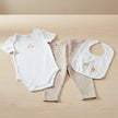Baby clothing set with onesie, pants, and bib featuring giraffe designs on a table